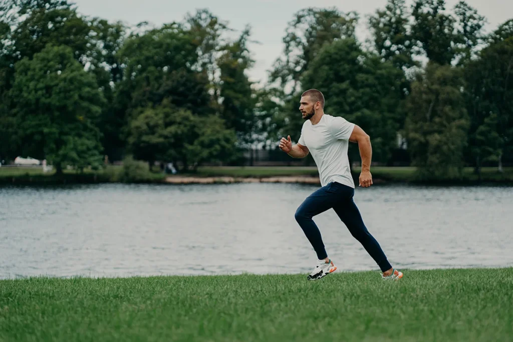 ACL Recosntruction worth it for active individuals - man running on grass near lake