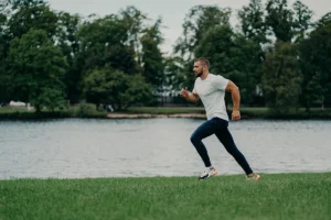 ACL Recosntruction worth it for active individuals - man running on grass near lake